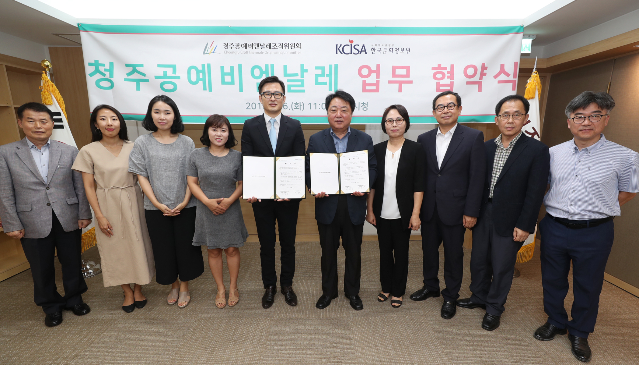 청주공예비엔날레조직위원회와 한국문화정보원의 임직원이 업무협약서를 들고 단체사진을 찍고있다.